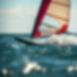 A close-up view of a sailboard gliding through the water, showcasing the vibrant colors of the sail and the dynamic movement of the board.